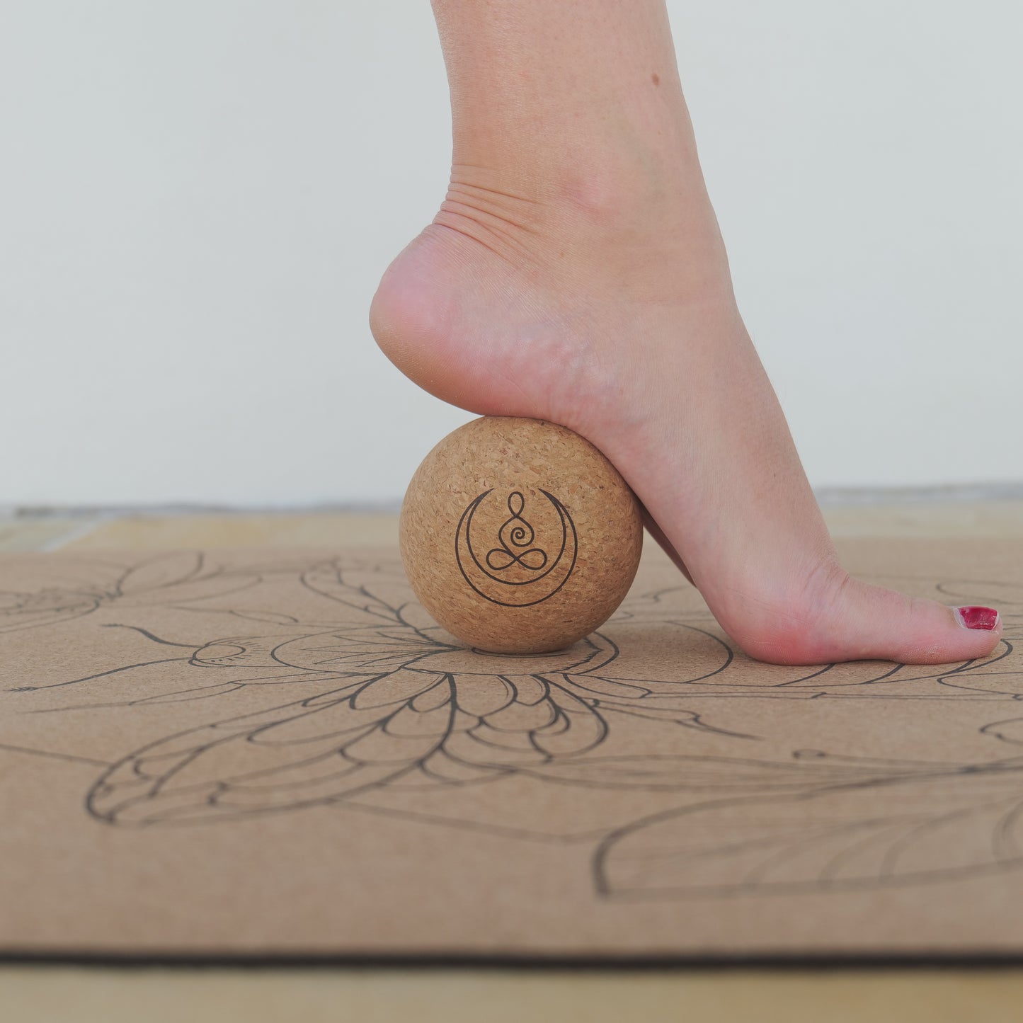 Woman using cork massage balls with OGI NEST logo for sole of foot.