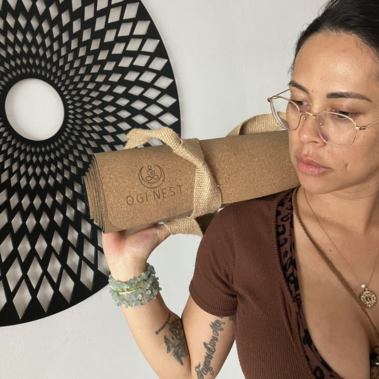 Pandora Hayes holding rolled-up moon serpent cork and natural rubber yoga mat with jute carry strap.