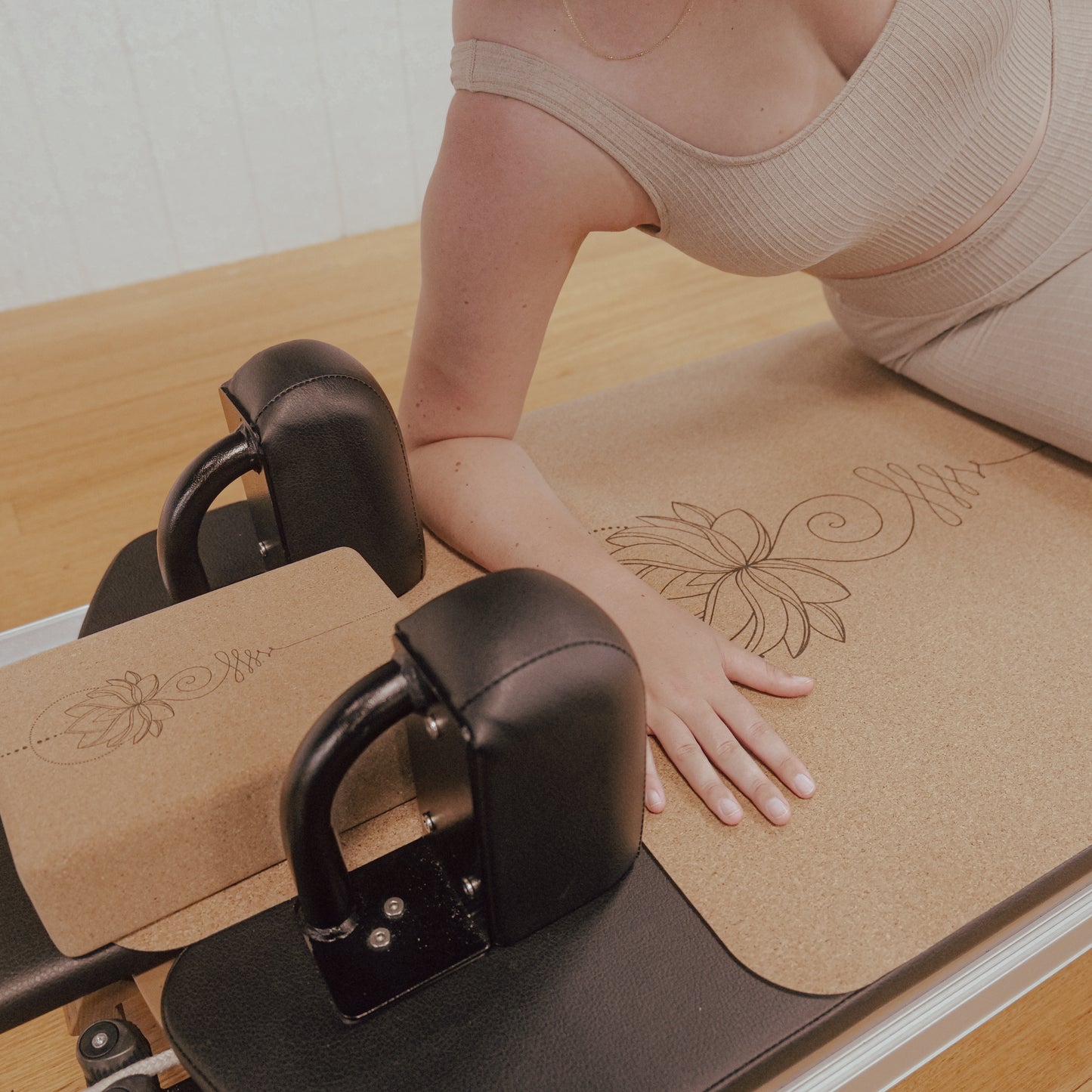 Woman resting on right forearm on unalome lotus cork and natural rubber Pilates reformer mat.