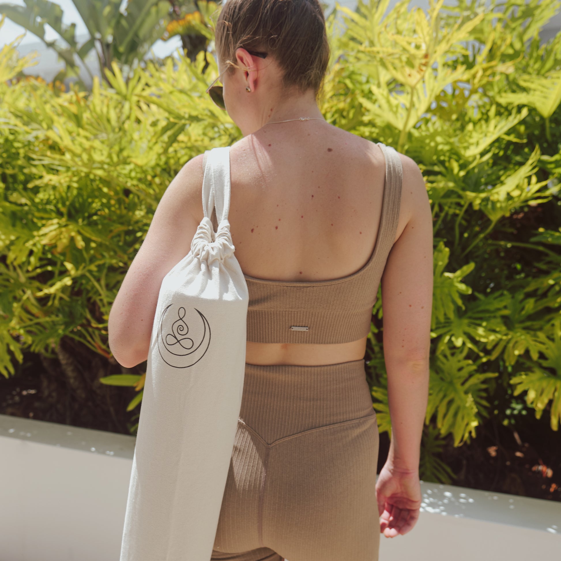 One woman wearing OGI NEST cotton canvas yoga mat carry bag.