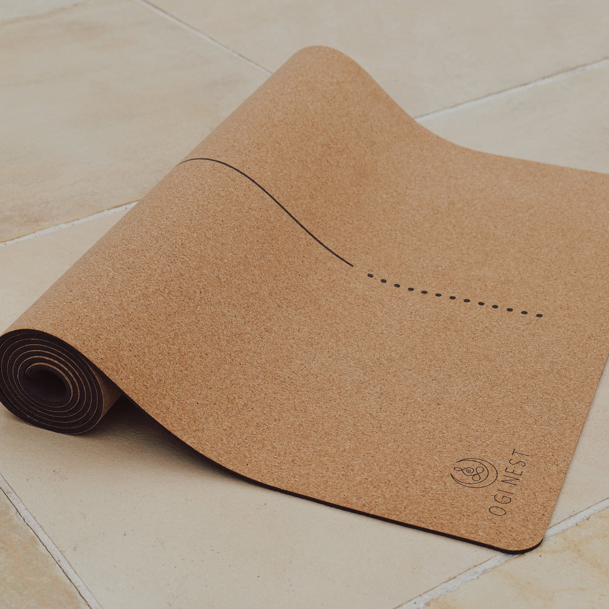 Unalome lotus cork and natural rubber yoga mat partially rolled up.