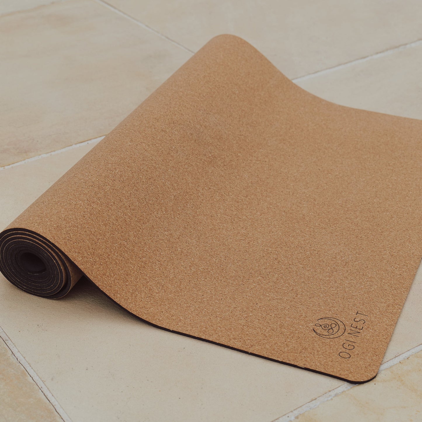 Hamsa hand cork and natural rubber yoga mat partially rolled up.