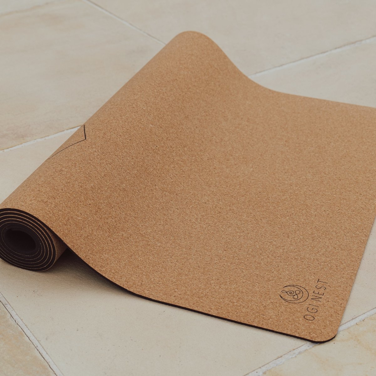 Bee cork and natural rubber yoga mat partially rolled up.