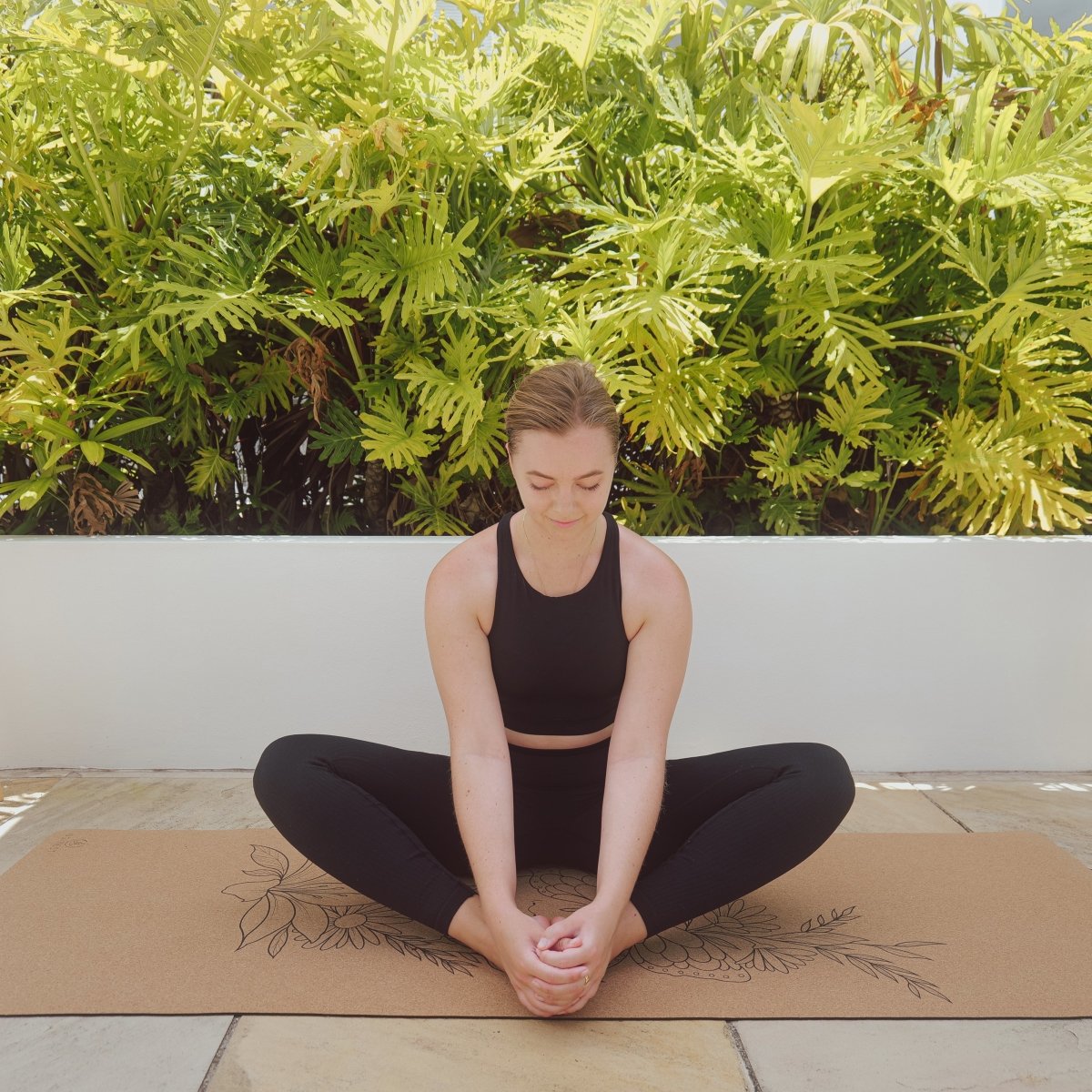 Woman performing butterfly pose on butterfly cork and natural rubber yoga mat.